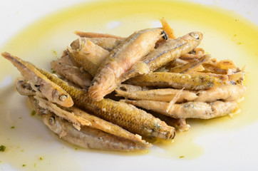 Fried fish with oil on a white plate