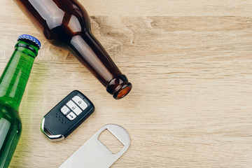 do not drink and drive concept, two bottles of beer and a remote car key with a stainless steel bottle opener or bar blade on wooden table