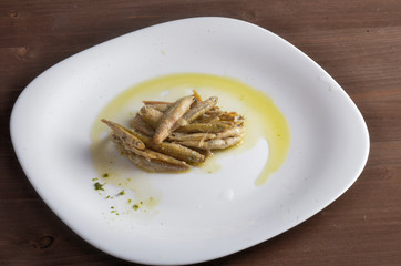 Fried fish with oil on a white plate