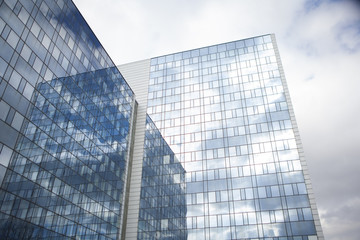 Fototapeta premium MAN Office building glass and steel with reflection of a perfect cloudy sky cbd downtown business district closing deals skyline