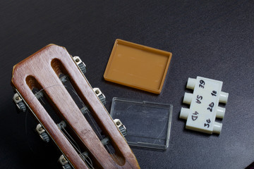 The fretboard of the acoustic guitar and the tuning fork to adjust it. On a dark background.