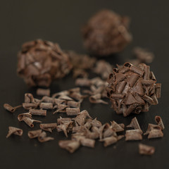 dark chocolate brigadeiro brazilian sweet with chocolate curls on black background