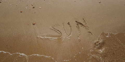 written on the sand at the seaside the word sun synonymous with holidays and relaxation