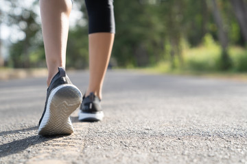 Runner feet running on road closeup on shoe. Woman fitness sunrise jog workout welness concept....