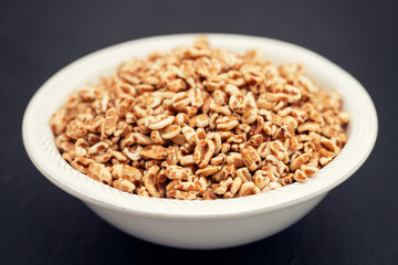 puffed spelt in white bowl on ceramic background