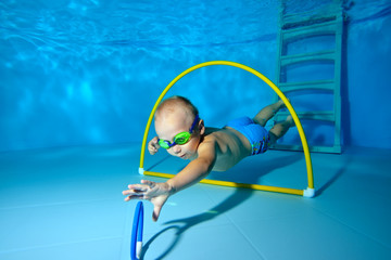 A little boy is engaged in scuba diving in the pool and dives to the bottom for toys. Portrait. Shooting underwater. Horizontal orientation © alexbard