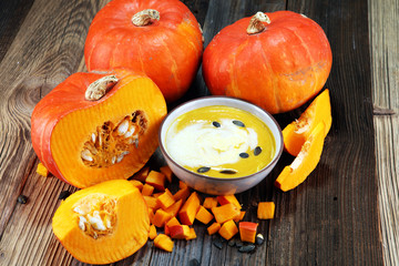 Roasted pumpkin and carrot soup with cream and pumpkin seeds on table.