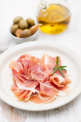 prosciutto on dish with olive oil and olives