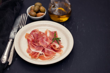 prosciutto on dish with olive oil and olives