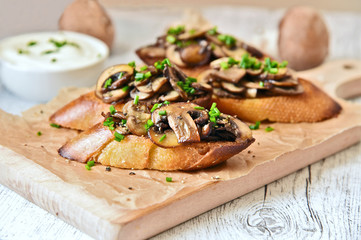 Champignon or brown cap mushroom Crostini on brown paper and wooden board.