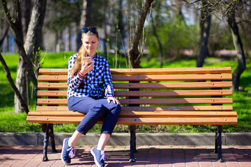 Young woman using mobile phone while sitting on bench in park