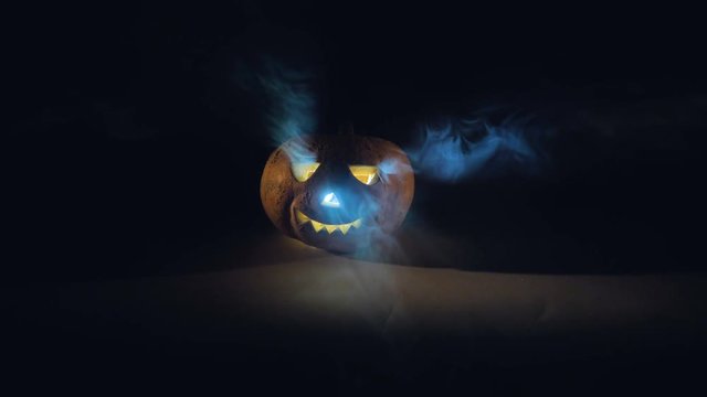 Decorative halloween pumpkin surrounded by smoke and darkness. Scary carved halloween pumpkin.