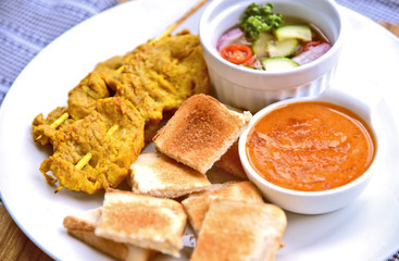 Pork satay set with toast and cucumber and red onion salad.