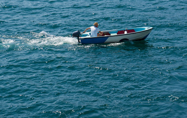 Fototapeta premium small motor boat sails on the blue waters of Lake Maggiore, Italy
