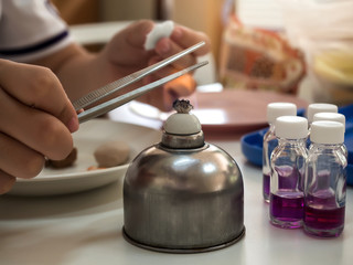 Close-up of tong being sterilized with an alcohol burner before use in lab. Medicine and microbiology concept.