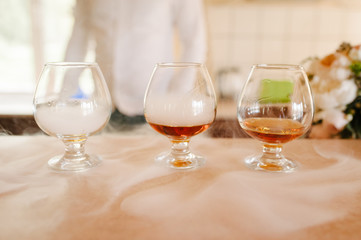 Glasses of whiskey with smoke on wooden table