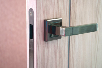 Open door in modern house. Modern wooden door with metal handle close-up detail. Interior product photography.