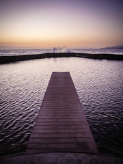 Obraz premium Jetty leading to the ocean at dusk with waves splashing against the sea wall in Tenerife