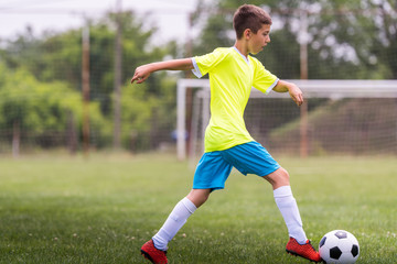 Boy kicking football on the sports field