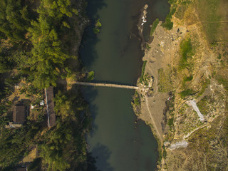 Green nature river with small bamboo bridge in Java village, Indonesia; aerial photography