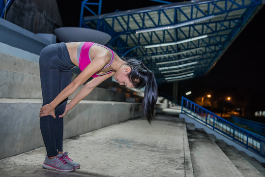 Asian slim girl stretching leg on stand night scene