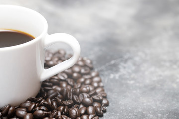 White coffee cup and coffee beans dark on table Bare mortar cement style loft background.