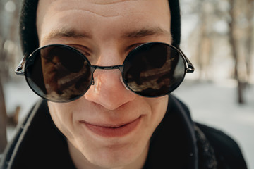 Handsome traveler man in a hat and round sunglasses. Travel and wanderlust concept. Hipster traveling. Portrait of emotion. Happy and ready. Space for text.