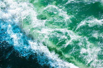 surface of turquoise ocean water with waves, spray and white foam