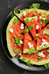 Grilled watermelon with cheese and greens on a concrete gray background. Summer dietary salad. View from above, flat lay.