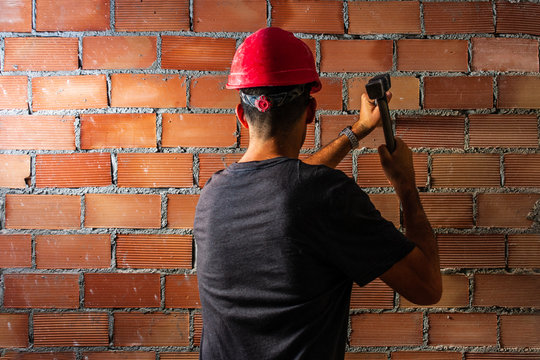 obrero con martillo y cincel trabajando en muro de ladrillos