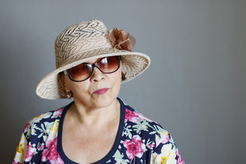 Eccentric elderly lady in a straw hat and sunglasses