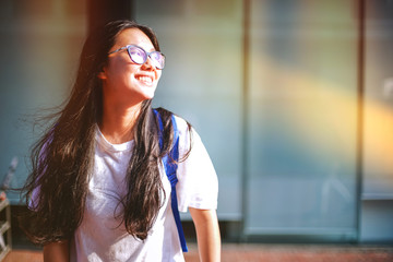 Portrait shot of beautiful young Asian female high school student smiling outdoor with light leaks from the sun light in the campus