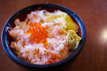 Tasty and delicious Donburi or Japanese rice bowl topped with boiled Kani(crab) garnished with Ikura(Salmon Roe) and wasabi at restaurant. Closeup. Selective Focus. Healthy Eating, Eat Well Concept.