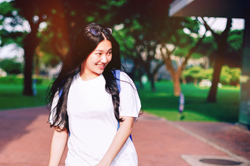 Portrait shot of beautiful young Asian female high school student smiling outdoor with light leaks from the sun light in the campus