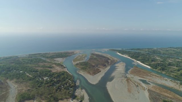 Aerial view of rver flowing into the sea in Philippines,Luzon. ropical landscape with sandy coast and river among farmer fields flowing into the blue ocean