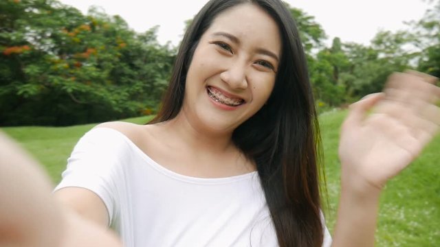 Beautiful asian young woman having video chat using smartphone outdoors sharing travel. Slow motion filmed.