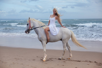 Sexy young woman walking with horse at the beach, horseback
