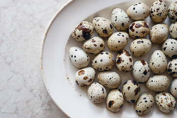 Obraz premium Delicious raw fresh quail eggs in white plate top view