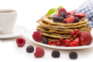 Delicious pancakes with berries and maple syrup on a white background