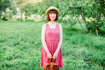 Obraz premium beautiful young woman in the garden. A girl in a straw hat. Portrait of a girl in a crimson dress smiles