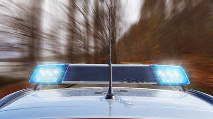 Polizeiwagen fährt im Herbst mit Blaulicht auf einer Landstraße