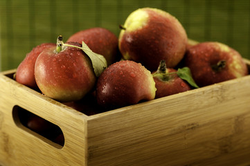 Apples with water droplets in small wooden crate