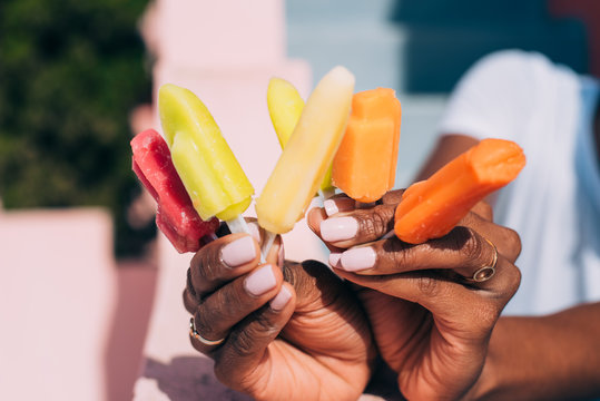 Black woman hands full of colorful popsicles