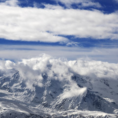 Fototapeta na wymiar Snow winter mountains in clouds at sun day