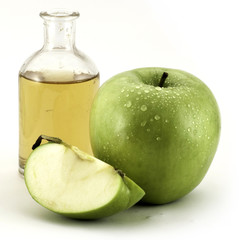 Green apple and apple vinegar in a glass bottle isolated on white