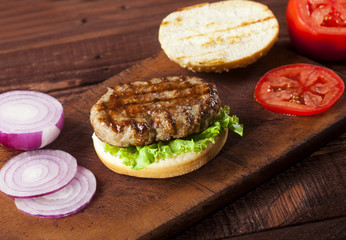 Fresh delicious burger ingredients on a wooden background