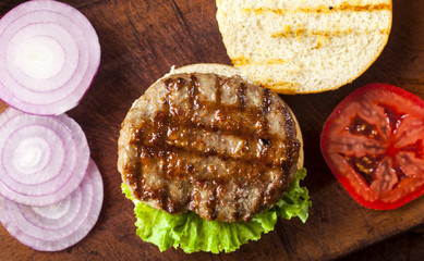Fresh delicious burger ingredients on a wooden background