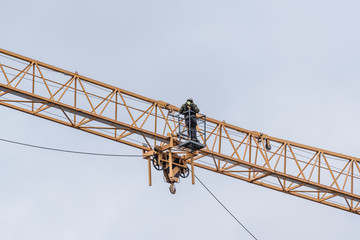 Worker makes technical check on a yellow building crane