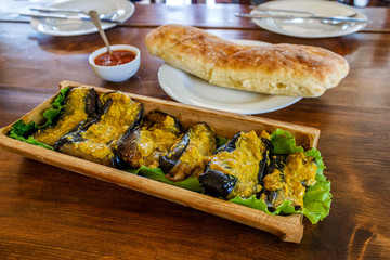 Fried aubergines with nut filling in a bowl of bamboo trunk. Aubergines in Georgian.