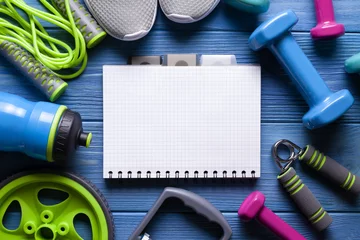 Gardinen Sport background - notebook and fitness equipment on blue wooden board © digieye